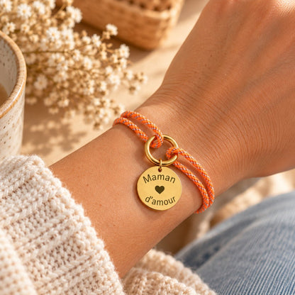 Bracelet personnalisé cordon orange porté au poignet, médaille gravée « Maman d'amour »