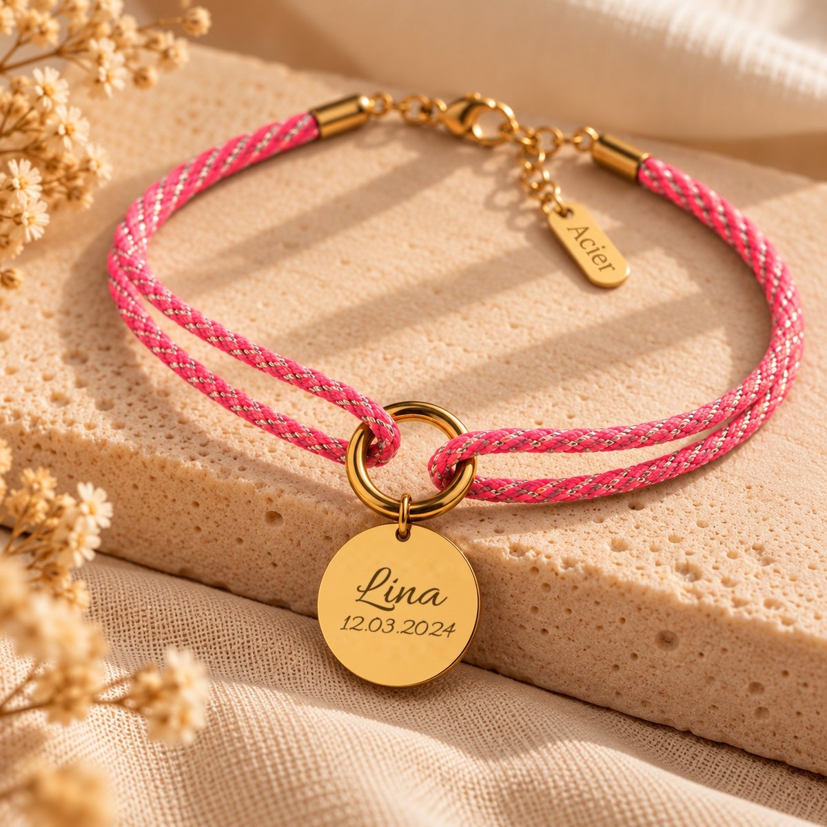 Bracelet cordon tressé rose et médaille dorée gravée d'un prénom et d'une date de naissance